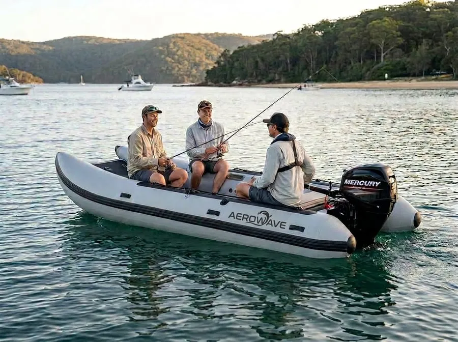 Real grey Aerowave inflatable catamaran on the water with anglers aboard; the driver sits at the stern on a side hull beside the outboard